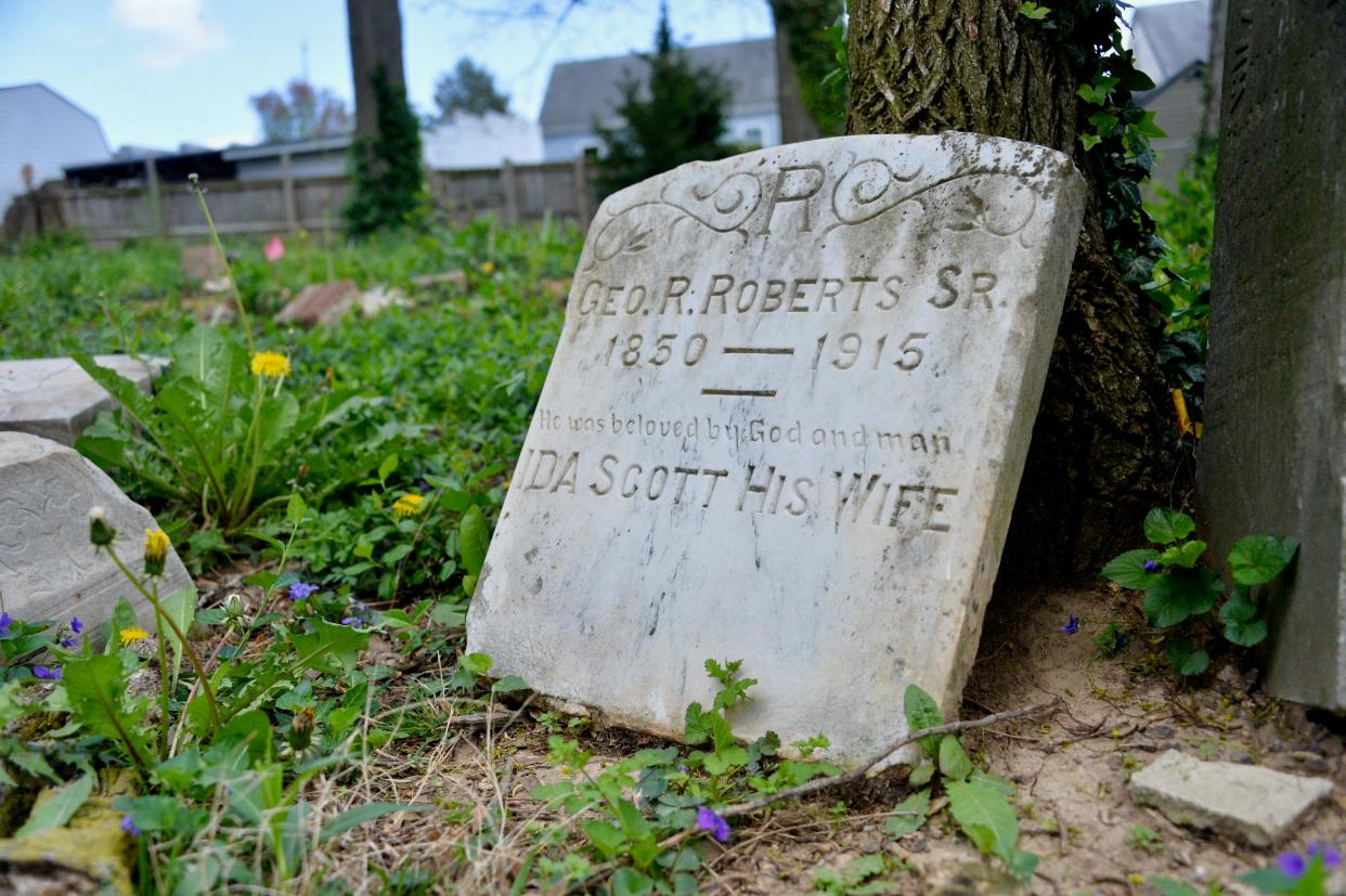 A tombstone leans against a tree in the Halfway African American Cemetery.