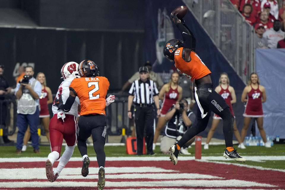 Oklahoma State linebacker Lamont Bishop (11) intercepts a pass intended for Wisconsin wide receiver Chimere Dike (13) during the first half of the Guaranteed Rate Bowl NCAA college football game Tuesday, Dec. 27, 2022, in Phoenix. (AP Photo/Rick Scuteri)
