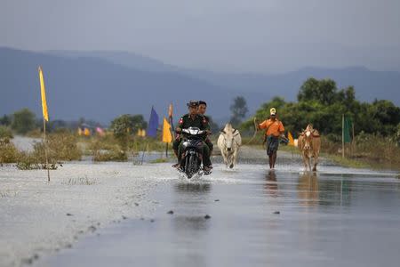 Soldiers ride a motorbike on a flooded road at Kawlin township, Sagaing division, Myanmar July 23, 2015. REUTERS/Soe Zeya Tun /Files