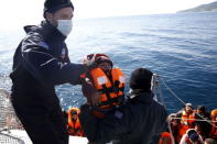 Greek Coast Guard officers move a baby from a dinghy carrying refugees and migrants aboard the Ayios Efstratios Coast Guard vessel, during a rescue operation at open sea between the Turkish coast and the Greek island of Lesbos, February 8, 2016. REUTERS/Giorgos Moutafis