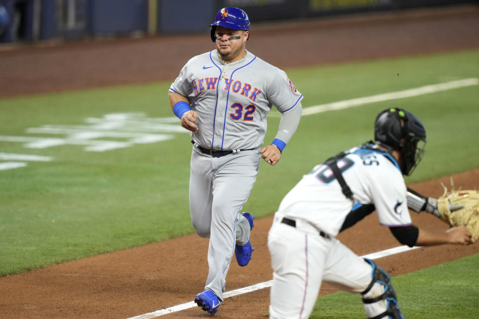 New York Mets' Daniel Vogelbach (32) scores past Miami Marlins catcher Jacob Stallings (58) on a sacrifice fly hit by Brandon Nimmo during the third inning of an opening day baseball game, Thursday, March 30, 2023, in Miami. (AP Photo/Lynne Sladky)