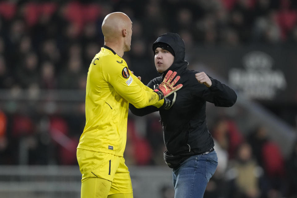 A PSV supporter attacks Sevilla's goalkeeper Marko Dmitrovic during the Europa League playoff second leg soccer match between PSV and Sevilla at the Philips stadium in Eindhoven, Netherlands, Thursday, Feb. 23, 2023. Sevilla won 3-2 on aggregate. (AP Photo/Peter Dejong)