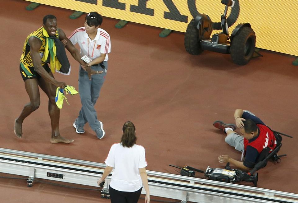 Winner Bolt  of Jamaica gets up after being hit by a cameraman on a Segway after competing at the men's 200 metres final during the 15th IAAF World Championships at the National Stadium in Beijing
