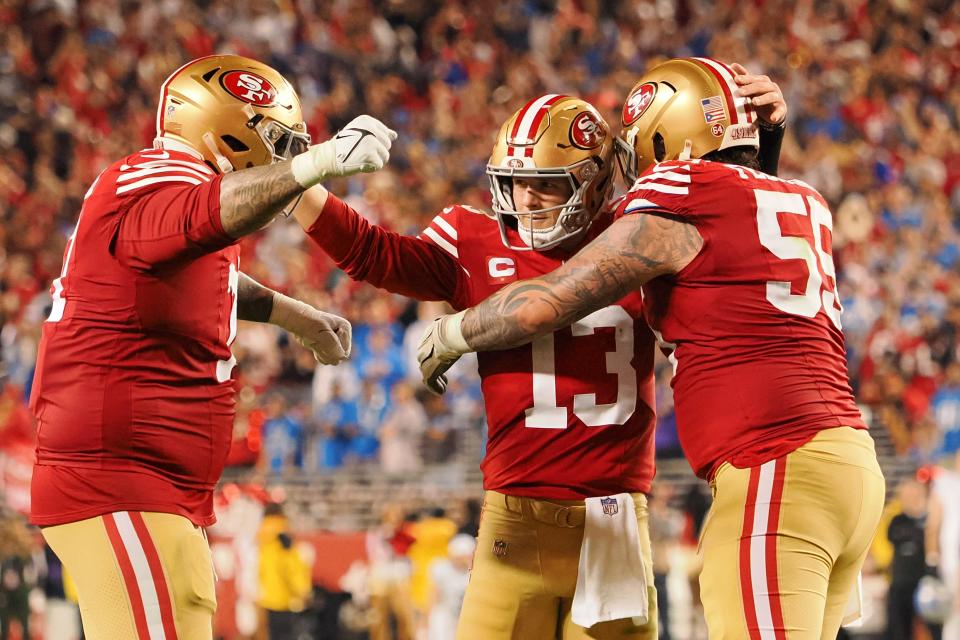 49ers quarterback Brock Purdy (13) celebrates with Jon Feliciano (55) and Trent Williams (71) after a play against the Detroit Lions.