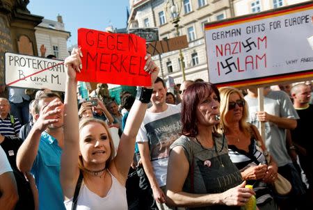 Protesters hold banners during a demonstration against German Chancellor Angela Merkel in Prague, Czech Republic, August 25, 2016. The banner reads, "Against Merkel". REUTERS/David W Cerny