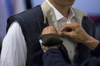 A tailor (R) marks a customer's new outfit with chalk before making the final touches inside a bespoke tailoring firm in Hong Kong February 11, 2015. REUTERS/Tyrone Siu
