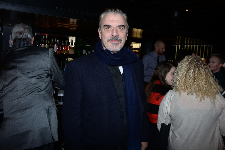 Noth looks into the camera inside a bar while wearing a scarf