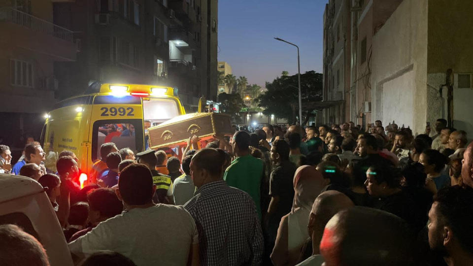 Crowds gather as a coffin is lifted into an ambulance to attend a memorial service for victims of a fire at a church in Greater Cairo that killed dozens on Sunday, Aug. 14, 2022. The blaze ignited at the Abu Sefein church in the densely populated neighborhood of Imbaba while a service was underway, according to the church. (AP Photo/Mohamed Salah)