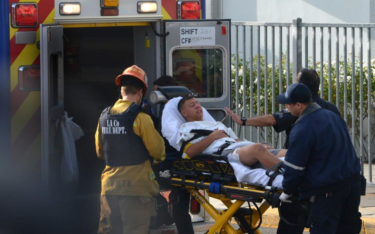 Medical personnel load an injured person into an ambulance outside Saugus High School in Santa Clarita - AP