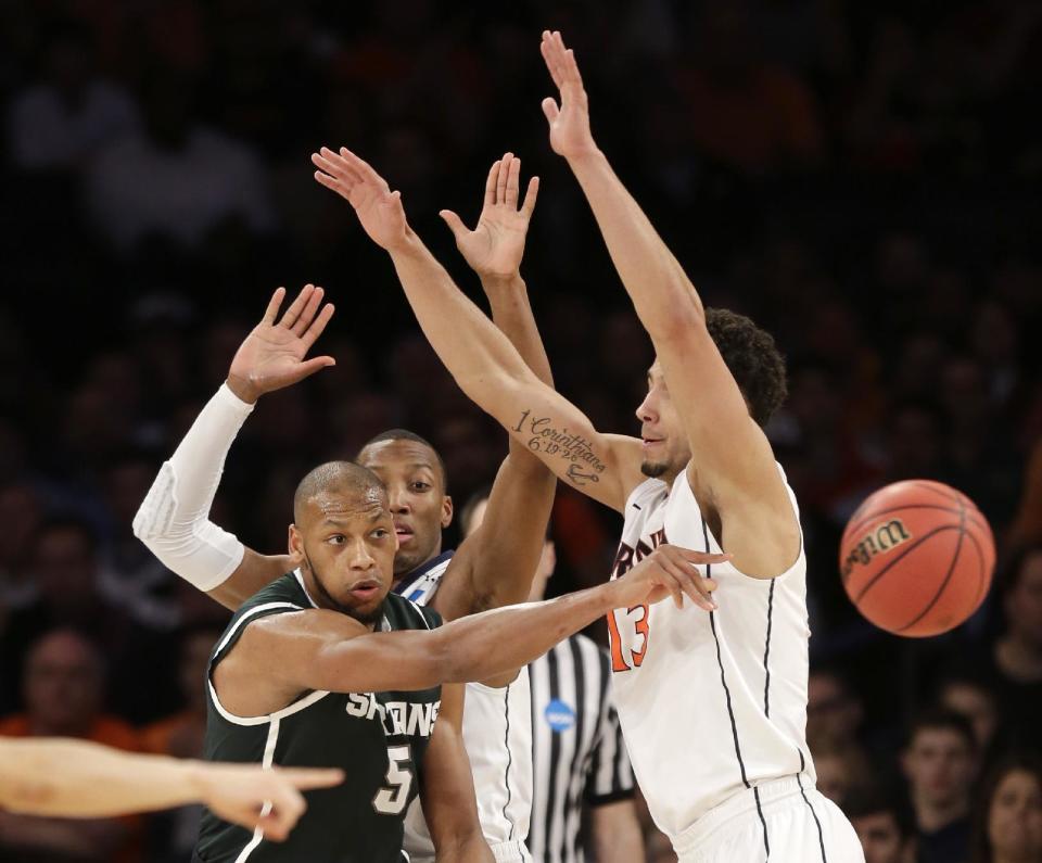 Michigan State's Adreian Payne passes the ball around Virginia's Anthony Gill during the second half of a regional semifinal at the NCAA men's college basketball tournament, Friday, March 28, 2014, in New York. (AP Photo/Seth Wenig)