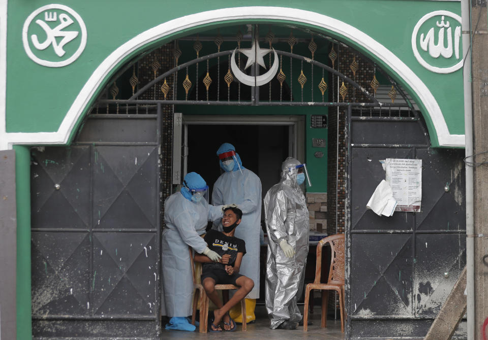 A Sri Lankan boy reacts as health officials take his nasal swab sample to test for COVID-19 outside a mosque in Colombo, Sri Lanka, Monday, Dec. 21, 2020. (AP Photo/Eranga Jayawardena)