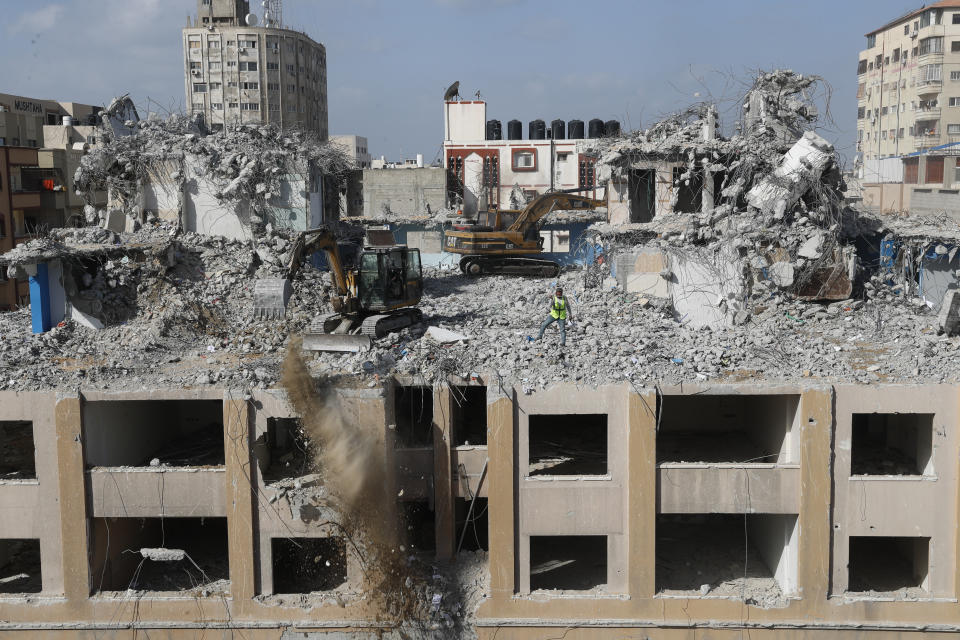 Palestinian workers use backhoes to break and remove parts of the Al-Jawhara building, which was damaged by Israeli airstrikes during Israel's war with Gaza's Hamas rulers last May, in the central al-Rimal neighborhood of Gaza City, Dec. 23, 2021. The Gaza Strip has few jobs, little electricity and almost no natural resources. But after four bruising wars with Israel in just over a decade, it has lots of rubble. Local businesses are now finding ways to cash in on the chunks of smashed concrete, bricks and debris left behind by years of conflict. (AP Photo/Adel Hana)