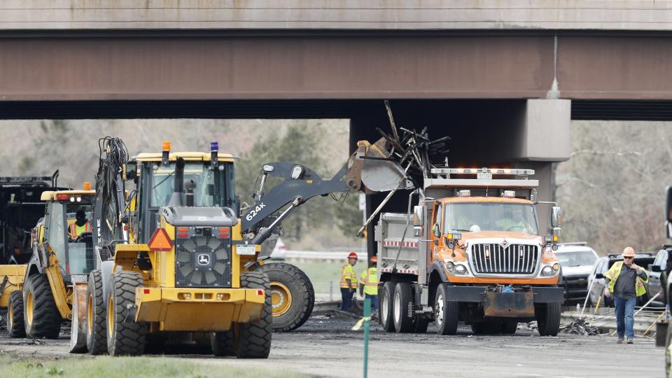 Workers clear debris from the eastbound lanes of Interstate 70 on Friday, April 26, 2019, in Lakewood, Colo., after a deadly pileup involving semi-truck hauling lumber on Thursday. Lakewood police spokesman John Romero described it as a chain reaction of crashes and explosions from ruptured gas tanks. "It was crash, crash, crash and explosion, explosion, explosion," he said. (AP Photo/David Zalubowski)