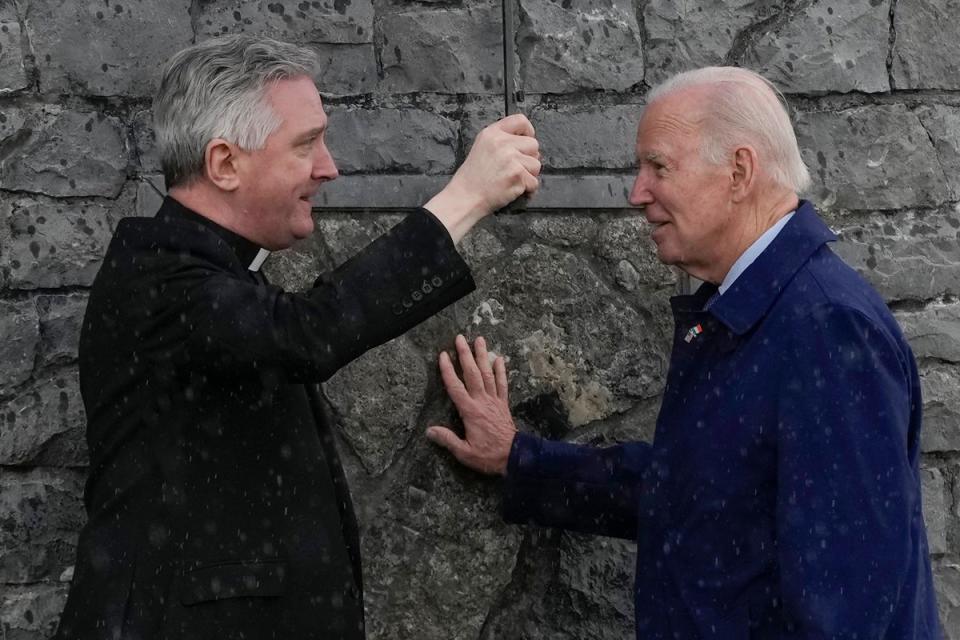 Mr Biden touches part of the original stonework from the apparition gable at the Knock Shrine as he talks with Father Richard Gibbons (Copyright 2023 The Associated Press. All rights reserved.)