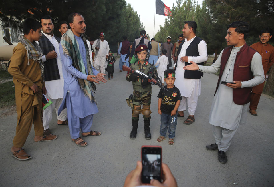 A man takes a picture of his son with an Afghan boy dressed as soldier during Independence Day celebrations in Kabul, Afghanistan, Monday, Aug. 19, 2019. Afghanistan's president is vowing to eliminate all safe havens of the Islamic State group as the country marks a subdued 100th Independence Day after a horrific wedding attack claimed by the local IS affiliate. (AP Photo/Rafiq Maqbool)