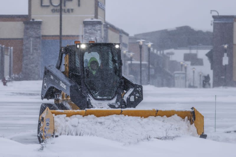 A worker clears snow from the parking lot of an outlet center in Altoona, Iowa, on Friday. Photo by Tannen Maury/UPI