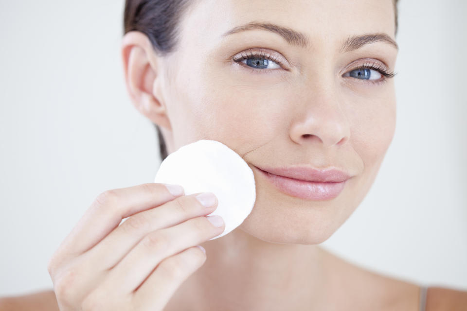 Woman holding a cotton pad near her face who is about to remove makeup and clean her face