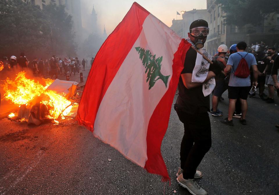 A protester stands with a Lebanese national flag during clashes with army and security forces near the Lebanese parliament (AFP/Getty)