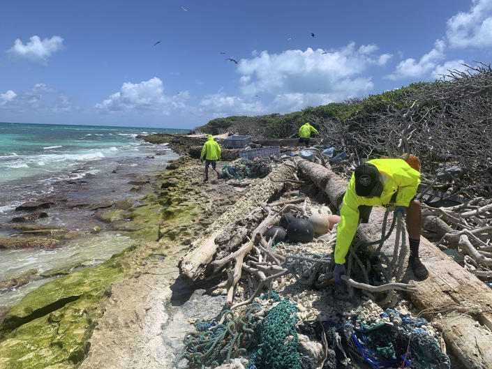 In this April 13, 2021 photo provided by Kevin O'Brien, workers with the Papahanaumokuakea Marine Debris Project remove fishing nets and plastic from the shoreline of Lisianski Island in the Northwestern Hawaiian Islands. A crew has returned from the remote Northwestern Hawaiian Islands with a boatload of marine plastic and abandoned fishing nets that threaten to entangle endangered Hawaiian monk seals and other marine animals on the tiny, uninhabited beaches stretching for more than 1,300 miles north of Honolulu. (Kevin O'Brien, Papahānaumokuākea Marine Debris Project via AP)