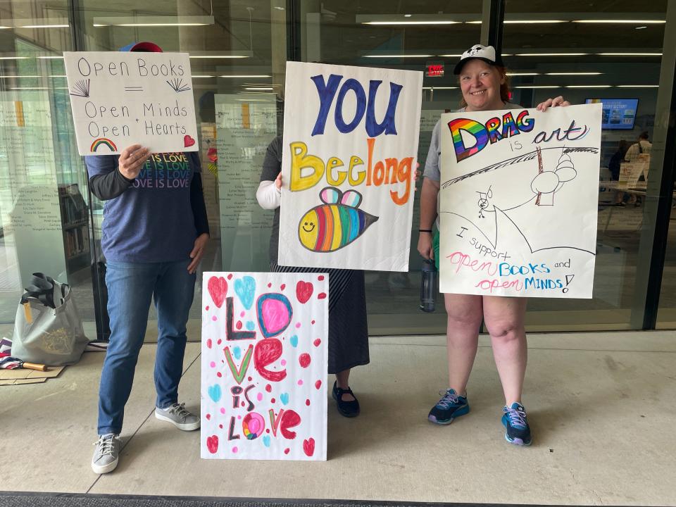 People hold signs outside of a drag story hour Sunday, May 21 at the Des Moines Central Public Library.