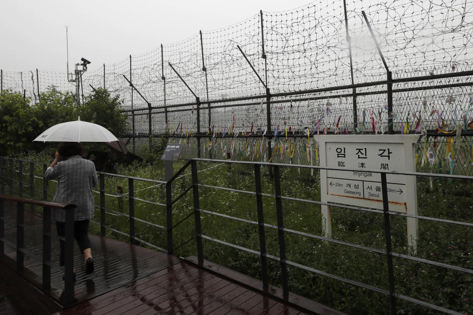 A woman walks in front of a directional sign showing the distance to North Korea's Kaesong city and South Korea's capital Seoul near the wire fences decorated with ribbons written with messages wishing for the reunification of the two Koreas at the Imjingak Pavilion in Paju, South Korea, Wednesday, June 24, 2020. North Korea said Wednesday leader Kim Jong Un suspended a planned military retaliation against South Korea, possibly slowing the pressure campaign it has waged against its rival amid stalled nuclear negotiations with the Trump administration. (AP Photo/Lee Jin-man)