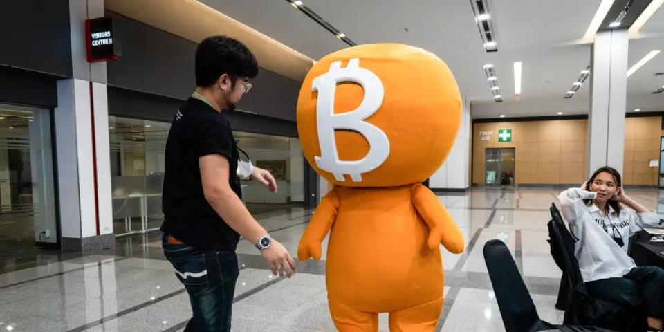 person interacting with a bitcoin logo mascot