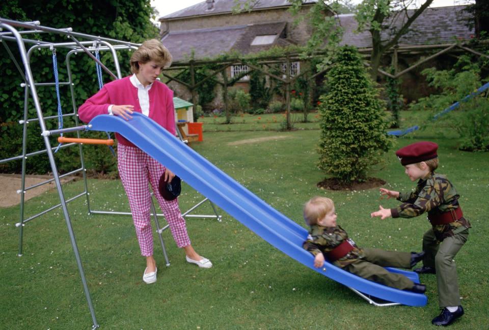 <p>Princess Diana plays with her sons on the playground at Highgrove House. The boys are dressed in their uniforms for the 1st Battalion of the Parachute Regiment, the group for which their father served as Colonel-in-Chief. </p>