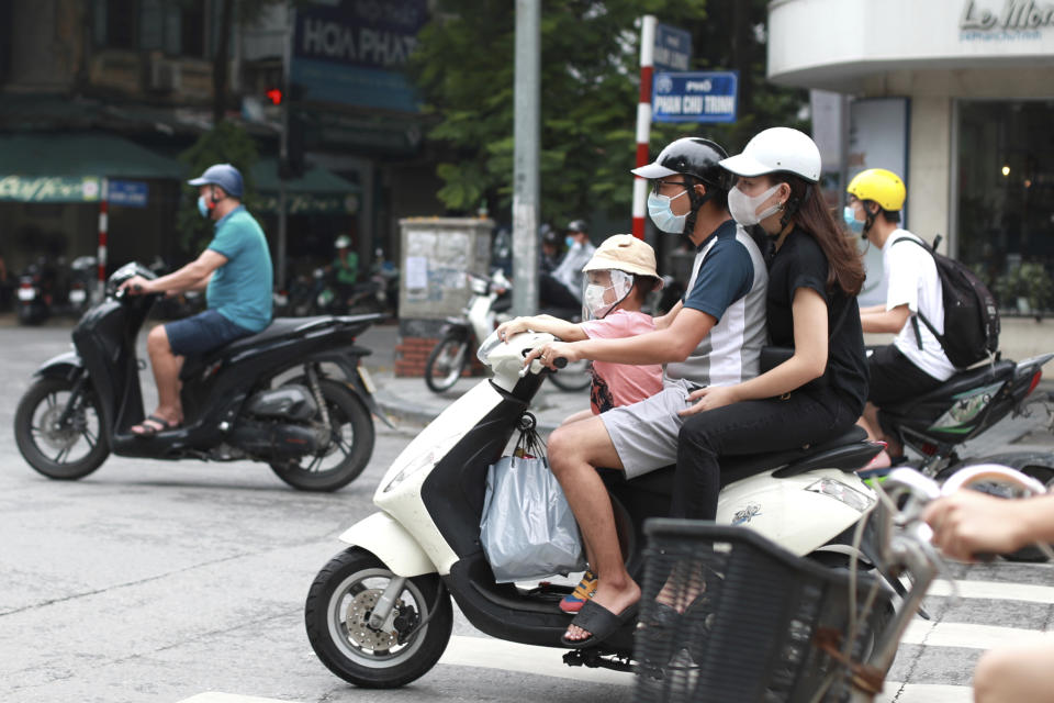 People wearing face masks ride motorcycles in Hanoi, Vietnam, Monday, Aug. 3, 2020. Vietnam has tightened travel and social restrictions after the country's death toll of COVID-19 to six. (AP Photo/Hau Dinh)