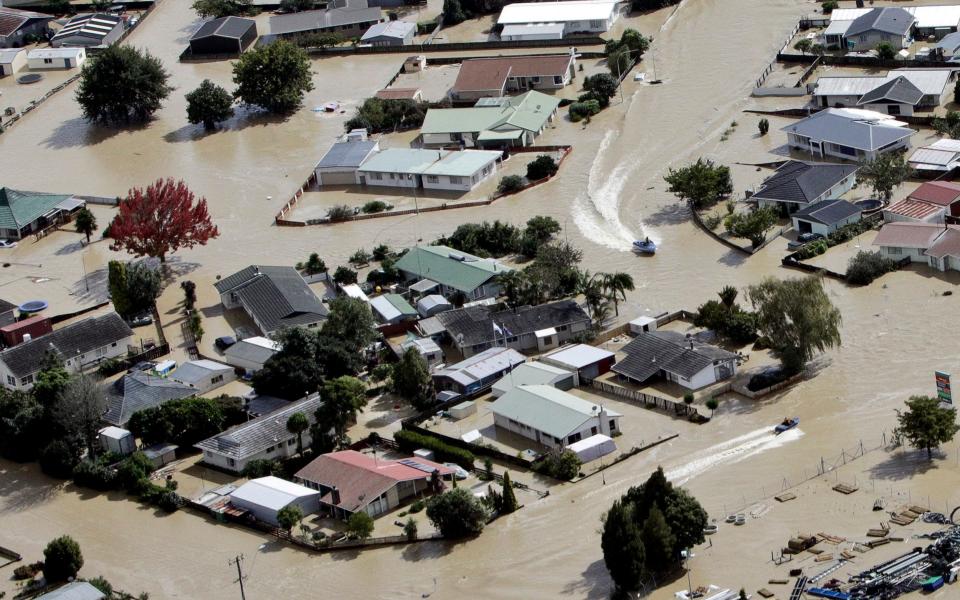 Jet boats drive through the flooded streets of the North Island town of Edgecumbe in New Zealand - Credit: Andrew Warner/AP