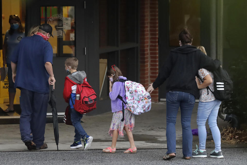 FILE - In this Aug. 3, 2020, file photo, students arrive to Dallas Elementary School for the first day of school amid the coronavirus outbreak in Dallas, Ga. For countless families across the country, the school year is opening in disarray and confusion, with coronavirus outbreaks triggering sudden closings, mass quarantines and deep anxiety among parents. (AP Photo/Brynn Anderson, File)