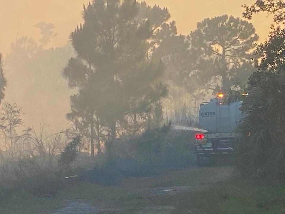 A Miami-Dade County water truck sprays down flames to keep a prescribed burn under control on SW 152nd Street in Palmetto Bay Wednesday, May 3, 2023.