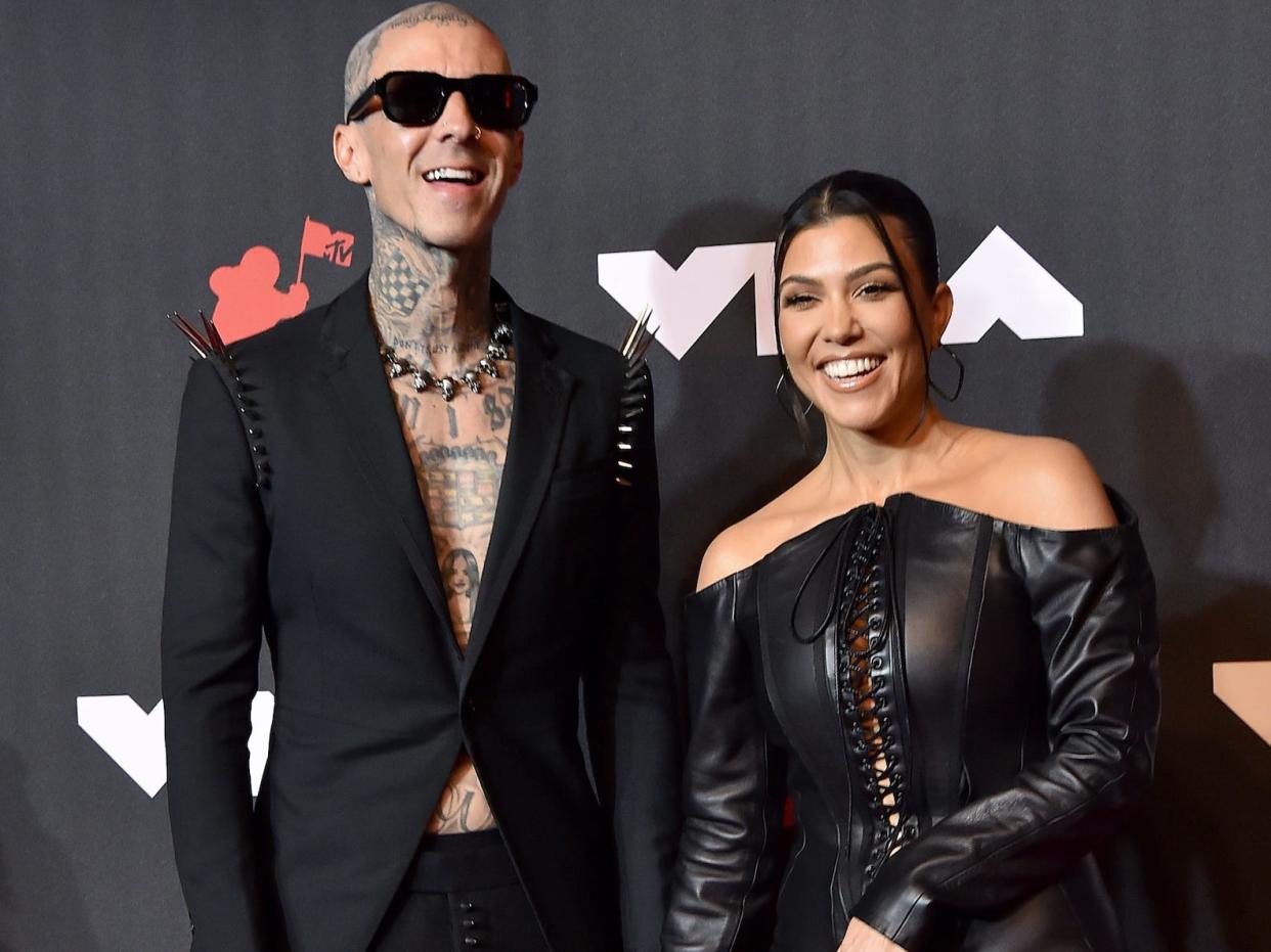 Travis Barker and Kourtney Kardashian smile on the VMAs red carpet.