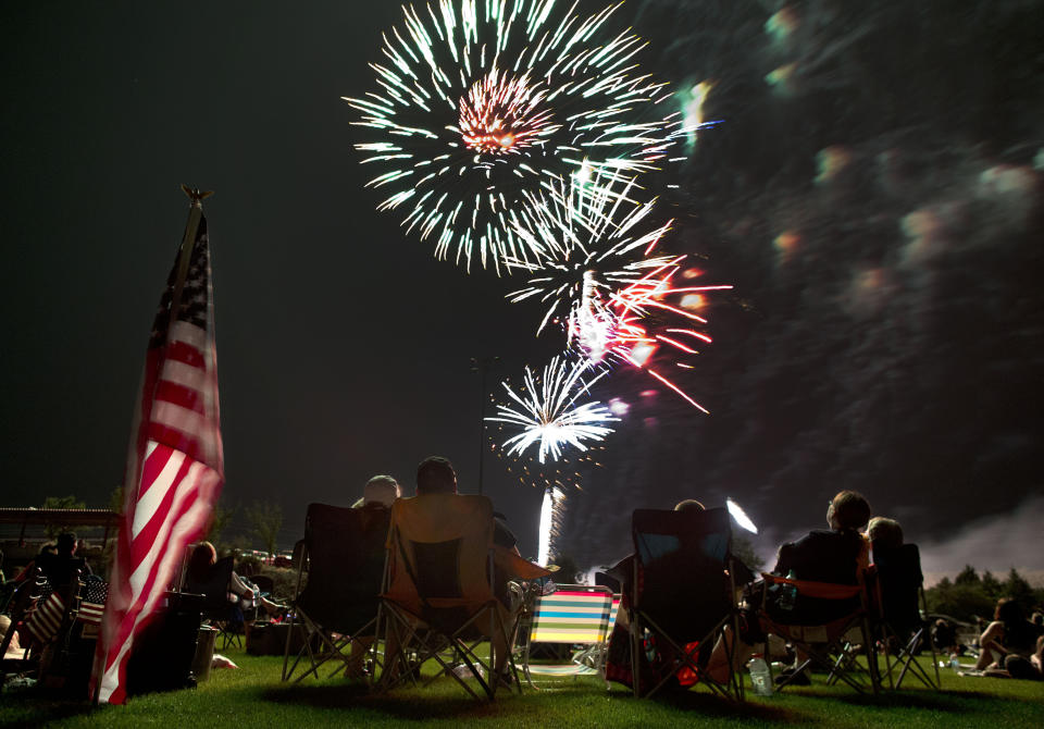 FILE - In this July 4, 2013, file photo, people watch as fireworks explode overhead during the Fourth of July celebration at Pioneer Park in Prescott, Ariz. For many Americans, the Fourth of July won't be about big festivities but setting off fireworks themselves. Hundreds of cities have canceled shows Saturday because of the coronavirus pandemic, and sales of consumer fireworks are booming. (AP Photo/Julie Jacobson, File)