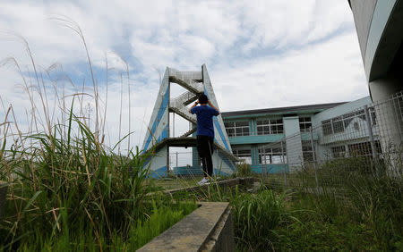 A tourist from Philippines takes photos at the Ukedo elementary school, damaged by the March 11, 2011 tsunami, at an area devastated by the disaster, near Tokyo Electric Power Co's (TEPCO) tsunami-crippled Fukushima Daiichi nuclear power plant, in Namie town, Fukushima prefecture, Japan May 17, 2018. Picture taken May 17, 2018. REUTERS/Toru Hanai