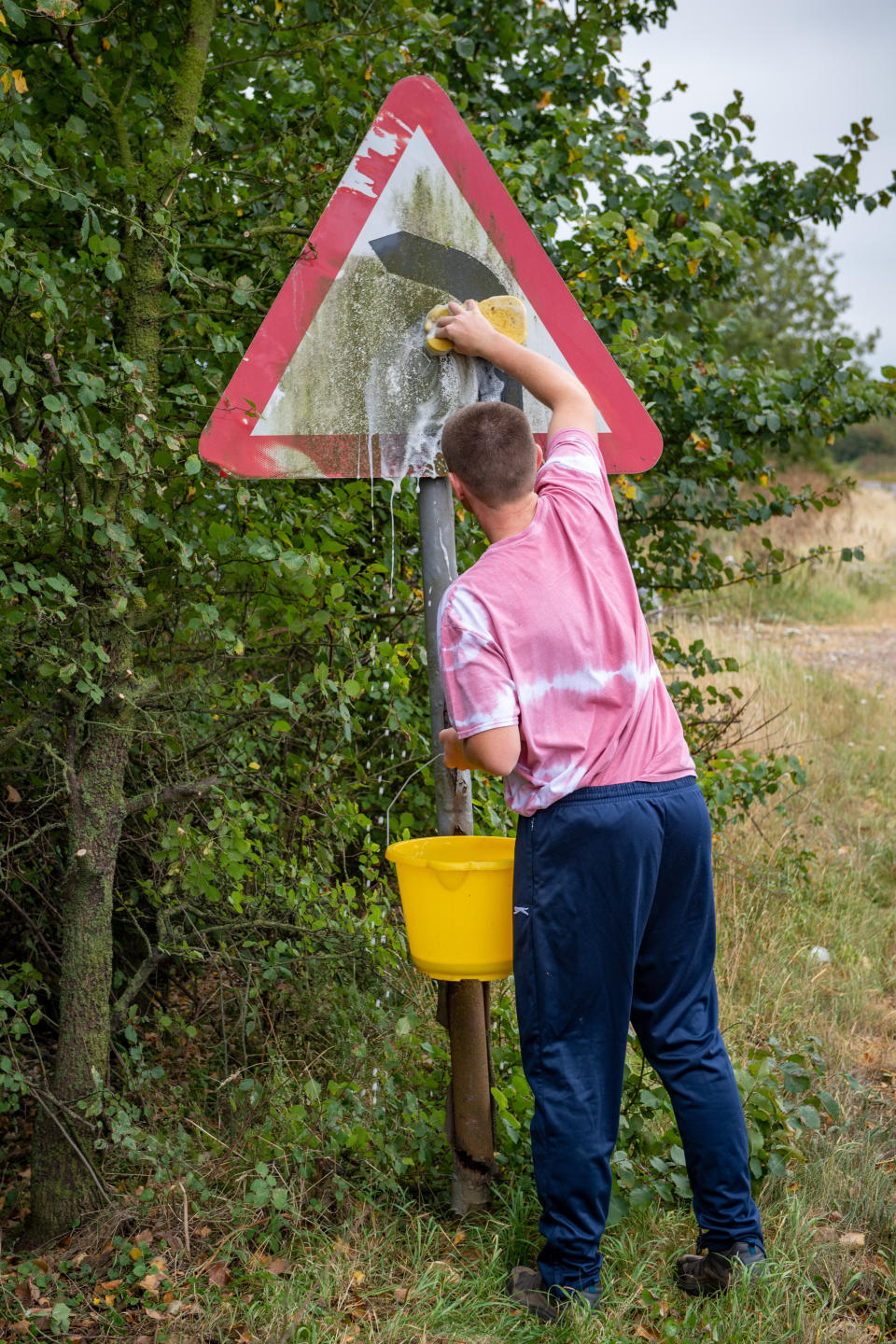 A teenage boy annoyed by road signs left dirty and hedges overgrown during lockdown has become a local hero after going on a mission to clean them all up. Joseph Beer, 15, noticed dozens of neglected street signs and hedgerows whilst out on his daily walks with mum Lisa, 52. He soon decided he wanted to clean up the streets - and with the help of dad Mark, 56, he rigged up a trailer to fix to the back of his bike, and started peddling around the streets near his house. Almost every day, Joseph, from Chatteris, Cambs., has headed off on his bike, towing a bucket of soapy water, some sponges, and garden tools, including hedgecutters and a rake, in the trailer.

His efforts have seen him clean up street name signs that have been left almost unreadable due to moss growing over them, such as Wilburton Road in nearby Ely.