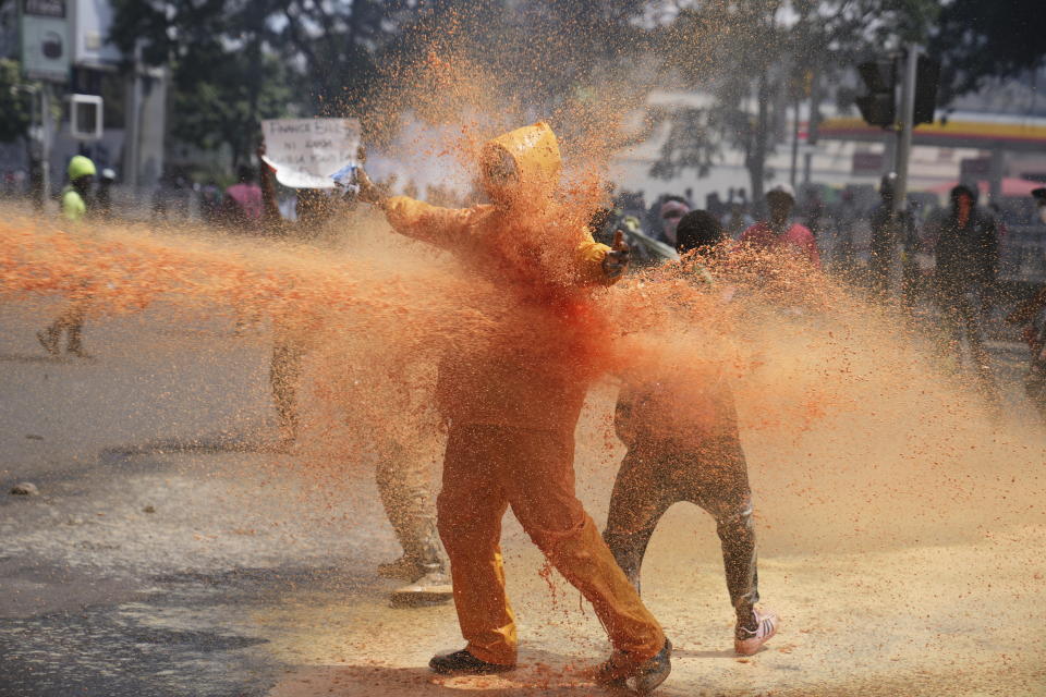 Protesters scatter as Kenya police spray a water canon at them during a protest over proposed tax hikes in a finance bill in downtown Nairobi, Kenya Tuesday, June 25, 2024. (AP Photo/Brian Inganga)