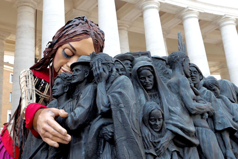 Little Amal, a 3.5 metre tall puppet of a young Syrian refugee girl, embraces the Angels Unawares scuplure in St. Peter's Square as she travels across Europe from Turkey to Britain as part of an 8,000 kilometre walk to raise awareness for the plight of young refugees, Vatican, September 10, 2021. REUTERS/Remo Casilli     TPX IMAGES OF THE DAY