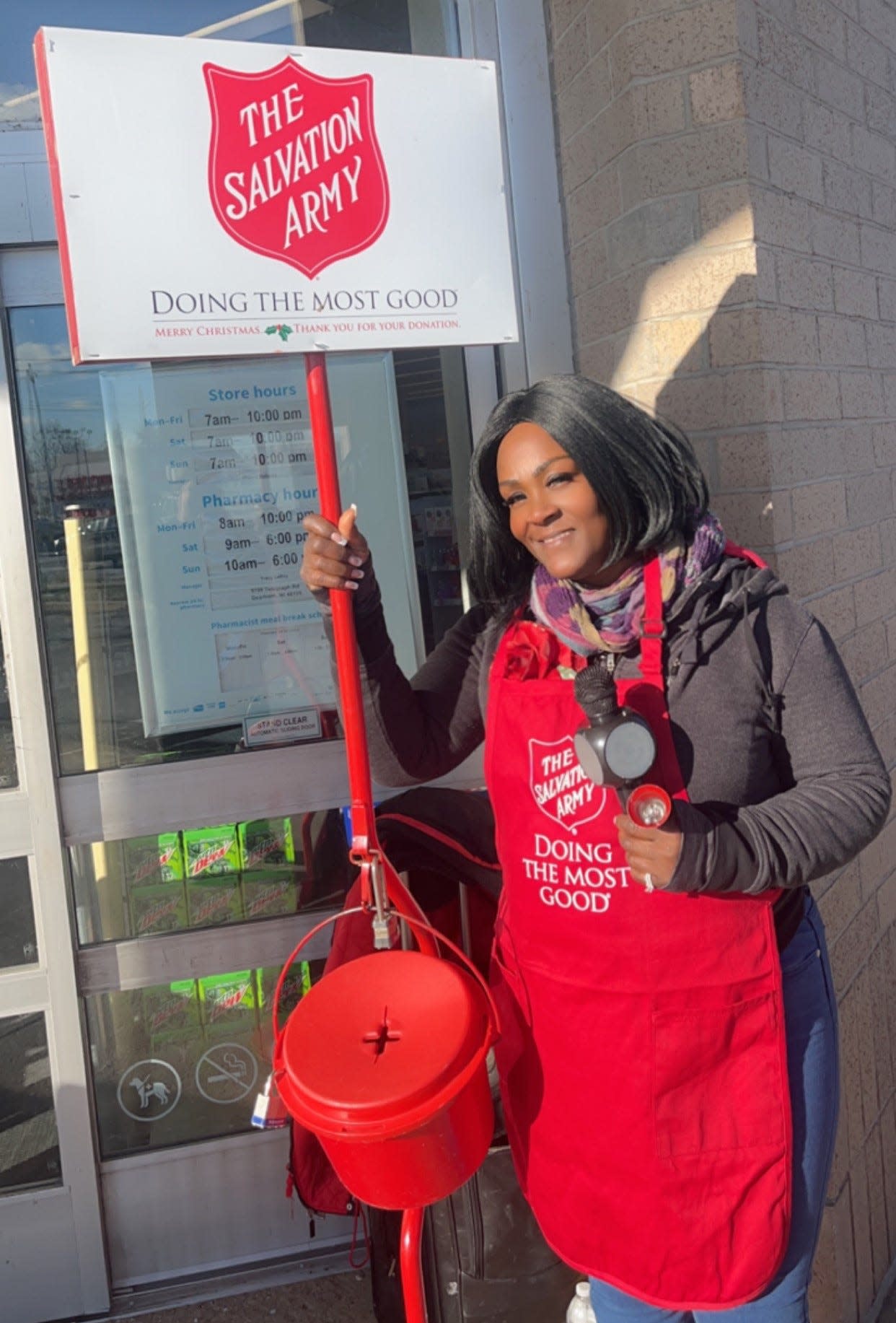 Wearing a red apron with a bell in one hand and a lighted karaoke-style microphone in the other, Articia Bomer is a singing Salvation Army bell ringer in Monroe.