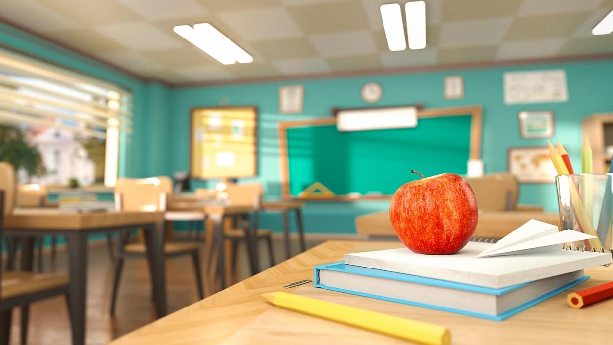 apple sitting on books on desk in classroom