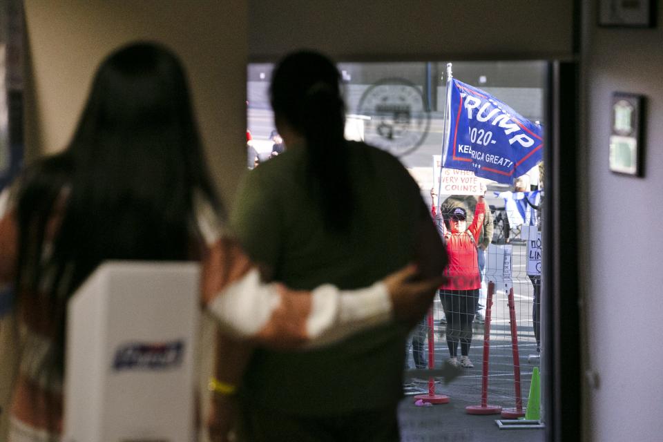 Maricopa County election workers look through a window as they watch several dozen protesters rally in support of President Donald Trump at the Maricopa County Elections headquarters in Phoenix on Nov. 9, 2020.