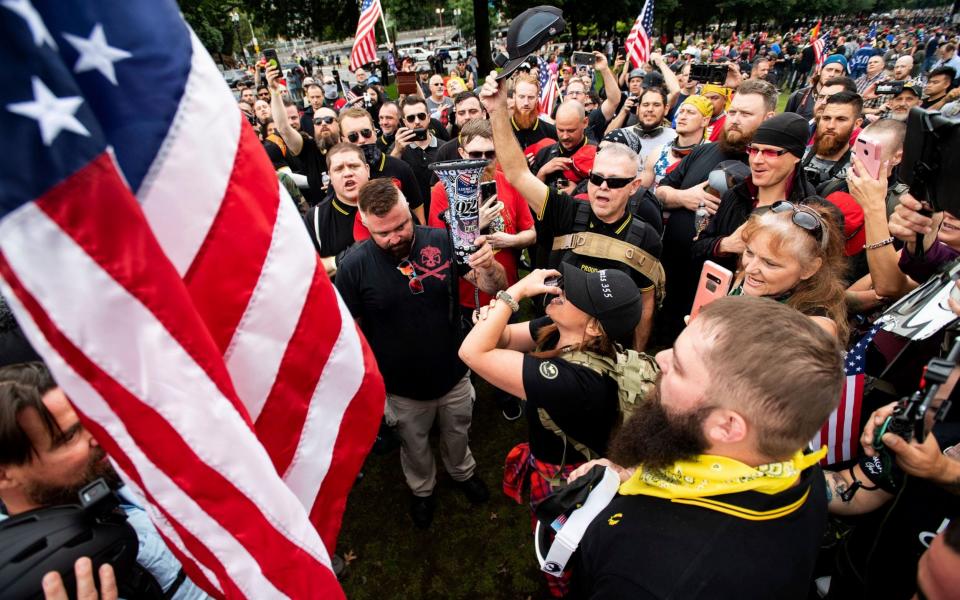 Members of the Proud Boys and other right-wing demonstrators plant a flag in Tom McCall Waterfront Park during a rally in Portland - Noah Berger