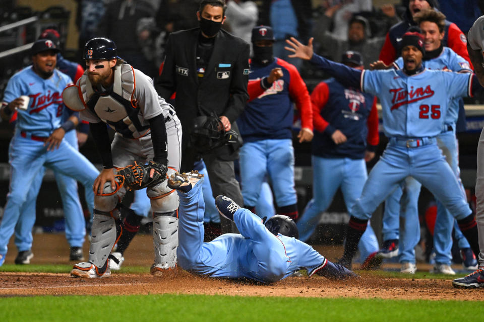 Apr 26, 2022; Minneapolis, Minnesota, USA; Minnesota Twins third base Gio Urshela (15) slides home for the game-winning run as teammates celebrate after a throwing error by Detroit Tigers catcher Eric Haase (13) during the ninth inning at Target Field. Mandatory Credit: Nick Wosika-USA TODAY Sports