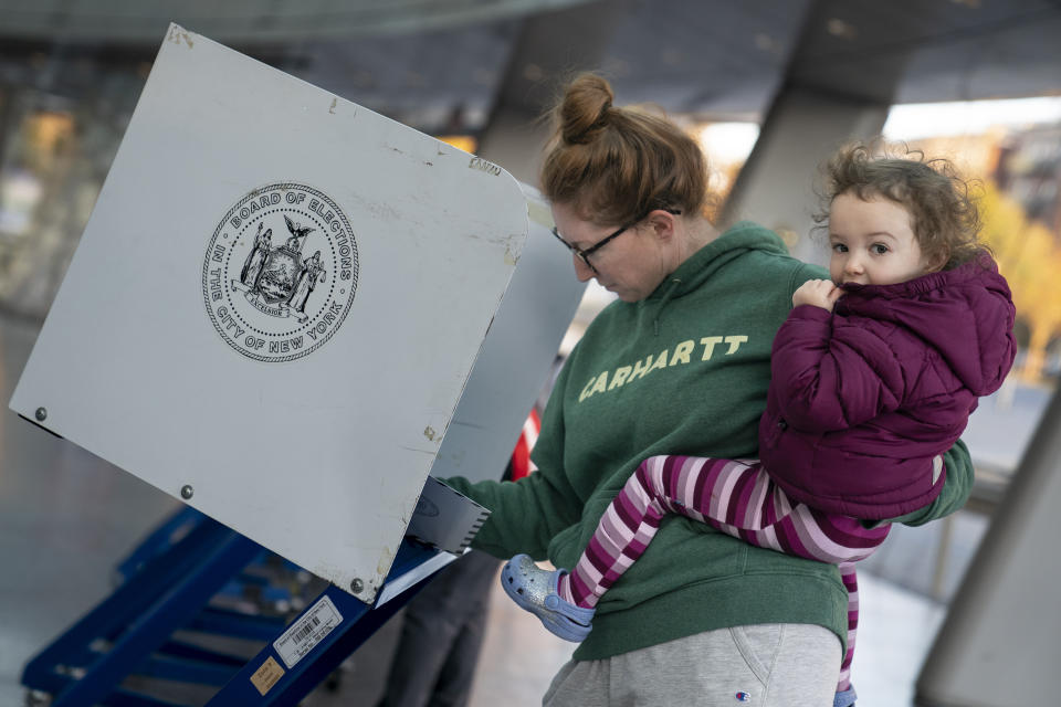 Kaitlin Farrell holds her daughter as she fills out her ballot at the Brooklyn Museum in New York.