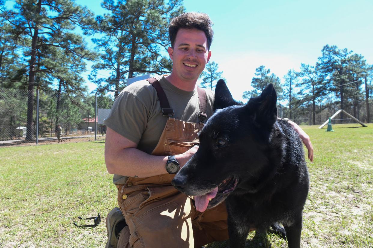 Staff Sergeant Robert Emfinger poses for a portrait with retired military dog Jager on Fort Eisenhower on Friday, March 29, 2024.