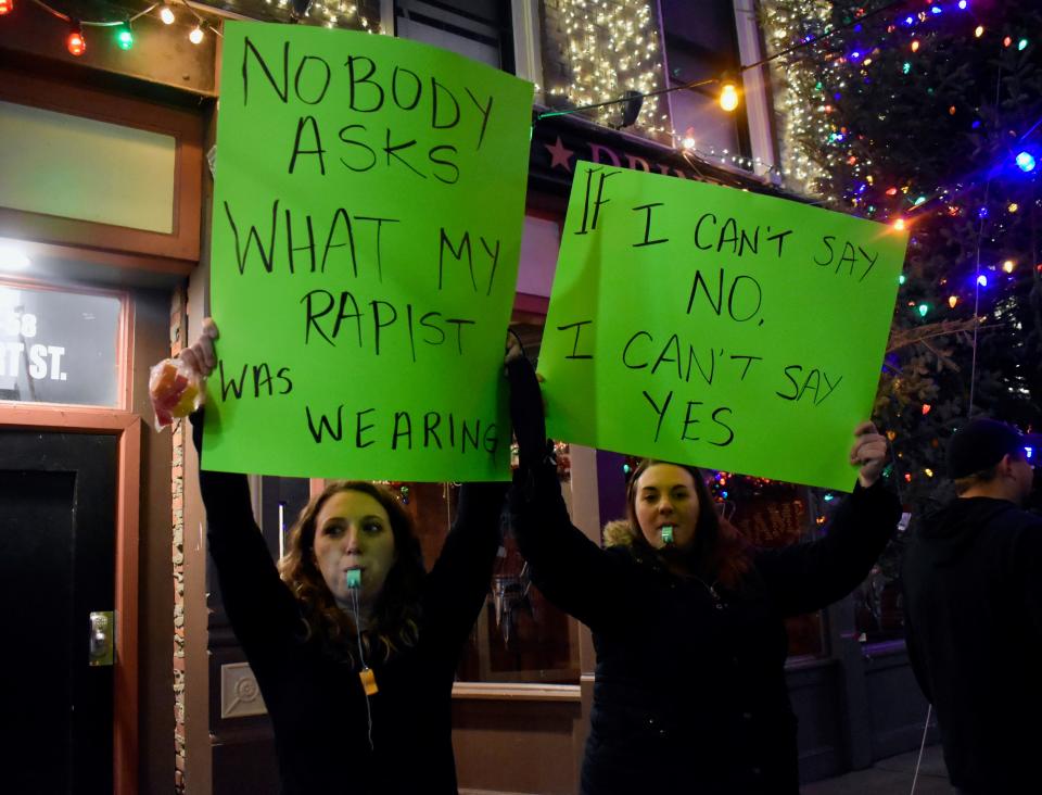 Union-Endicott native Ashley Trim, left, and a friend who declined to be identified, hold hand-drawn signs in front of the Colonial during a Friday, Dec. 31, protest on Court Street. The Colonial, Dos Rios Cantina and the Stone Fox were rumored to host an "all-you-can-drink" New Year's Eve bar crawl.