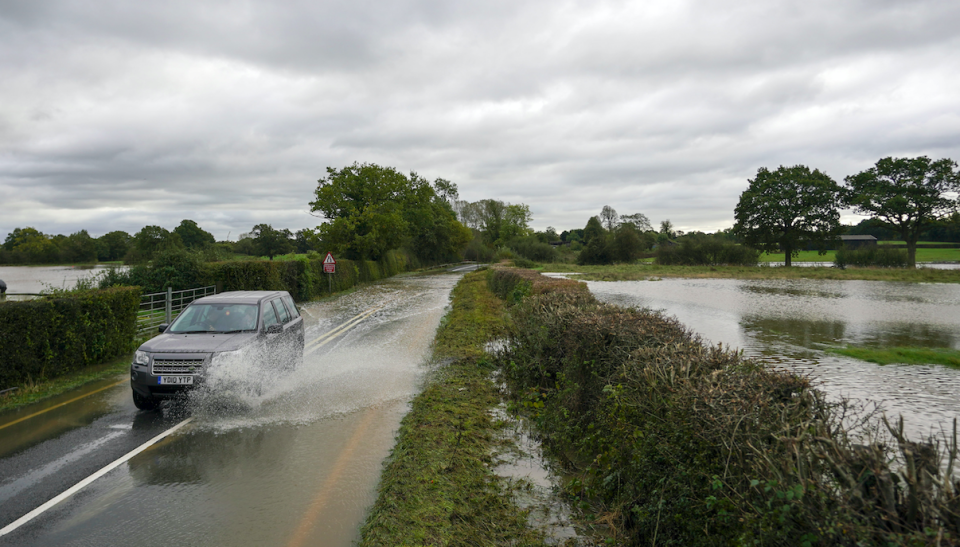 A 4x4 drives through flood water on a road in Lingfield, Surrey, on Thursday morning. (PA)