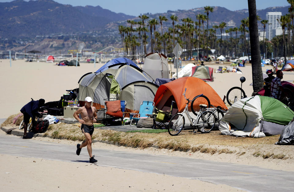 FILE - In this June 8, 2021, file photo, a jogger runs past a homeless encampment in the Venice Beach section of Los Angeles. By the end of the century, the U.S. population will be declining without substantial immigration, senior citizens will outnumber children and the share of white residents who aren't Hispanic will be less than half of the population, according to population projections released Thursday, Nov. 9, 2023 by the U.S. Census Bureau. (AP Photo/Marcio Jose Sanchez, File)