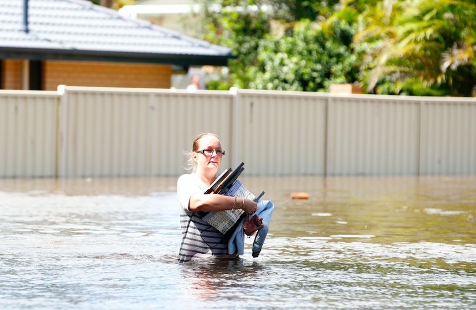 A south east Queensland woman carries belongings to safety during floods earlier this week. Photo: AAP