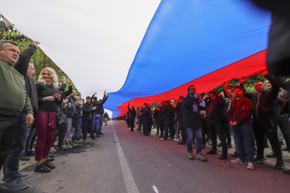 People hold a giant Serbian flag during a protest in front of the city hall in the town of Zvecan, northern Kosovo, Wednesday, May 31, 2023. Hundreds of ethnic Serbs began gathering in front of the city hall in their repeated efforts to take over the offices of one of the municipalities where ethnic Albanian mayors took up their posts last week. (AP Photo/Bojan Slavkovic)