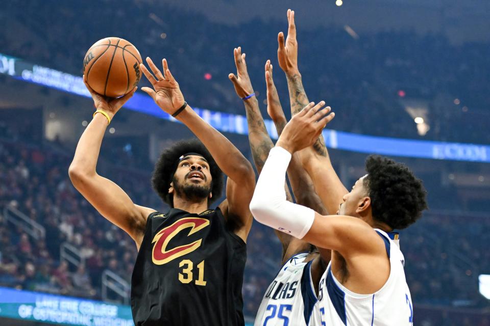 Cleveland Cavaliers center Jarrett Allen, left, shoots against forwards Reggie Bullock (25) and Christian Wood, right, during the first half of an NBA basketball game, Saturday, Dec. 17, 2022, in Cleveland. (AP Photo/Nick Cammett)